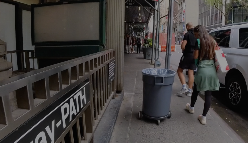 a robot trashcan on the sidewalk surrounded by woman walking