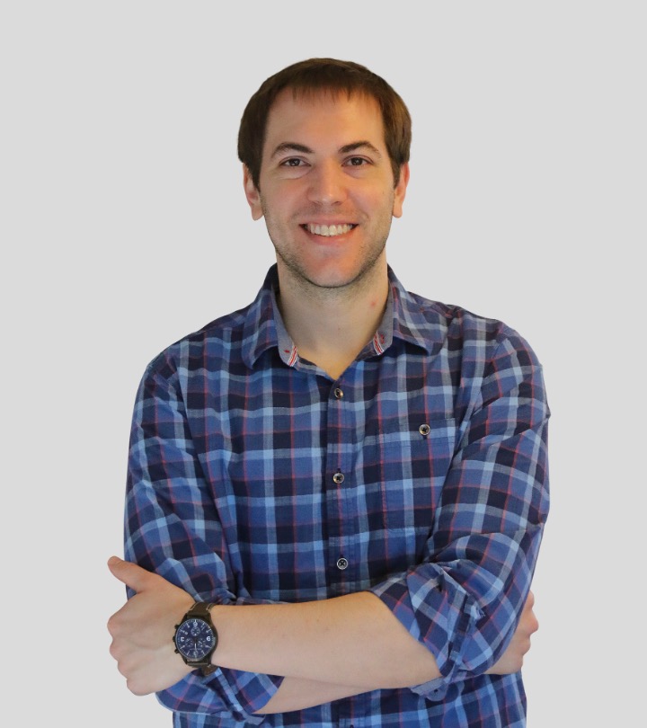 Man with short brown hair smiling at camera, wearing patterned shirt