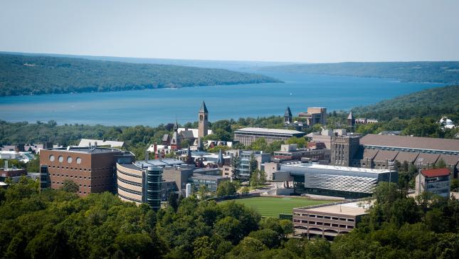 aerial view of cornell with buildings and a bright blue cayuga lake with green trees
