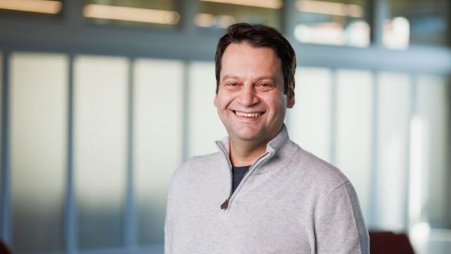 a man with short brown hair wearing a gray sweater