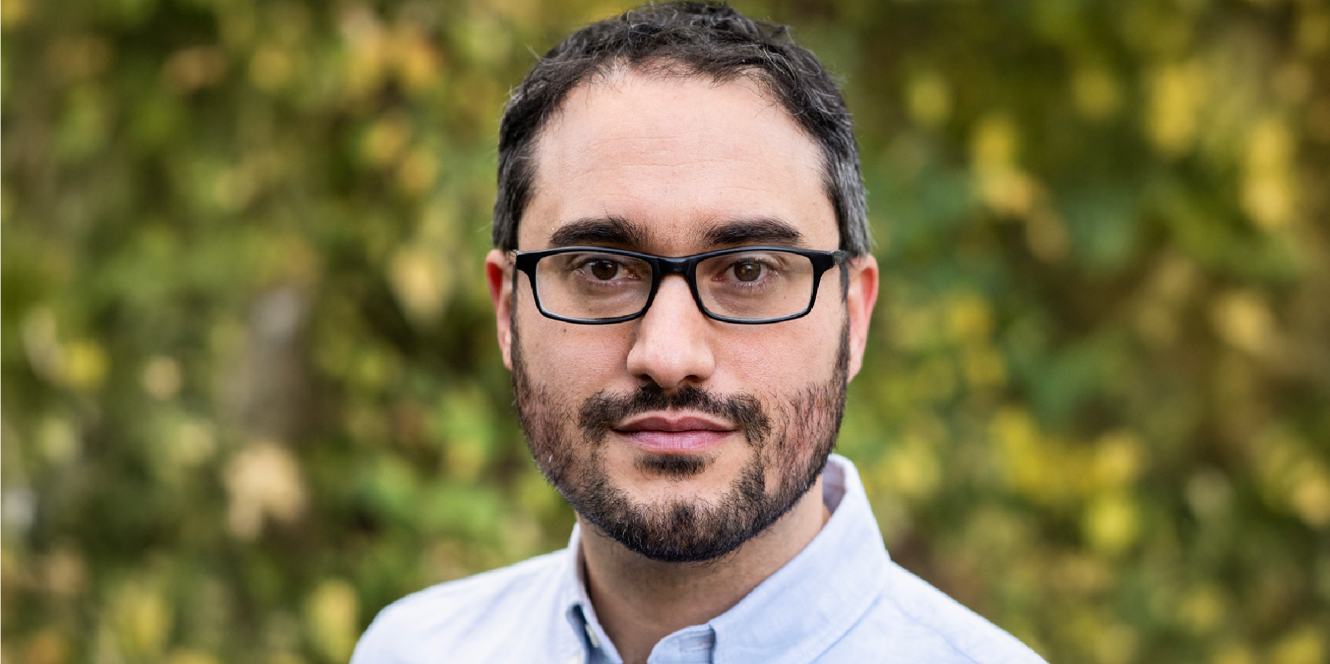 A color photo of a man standing outside.