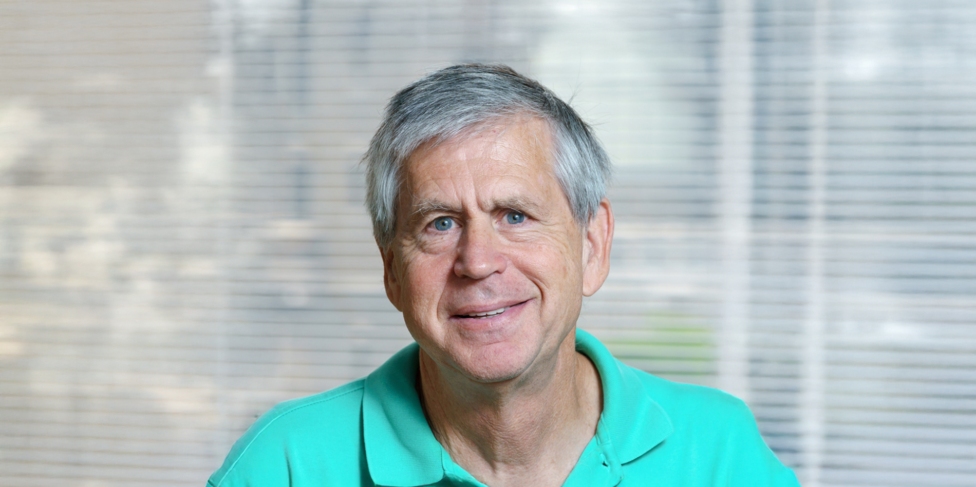 A color photo of a man in front of a window.