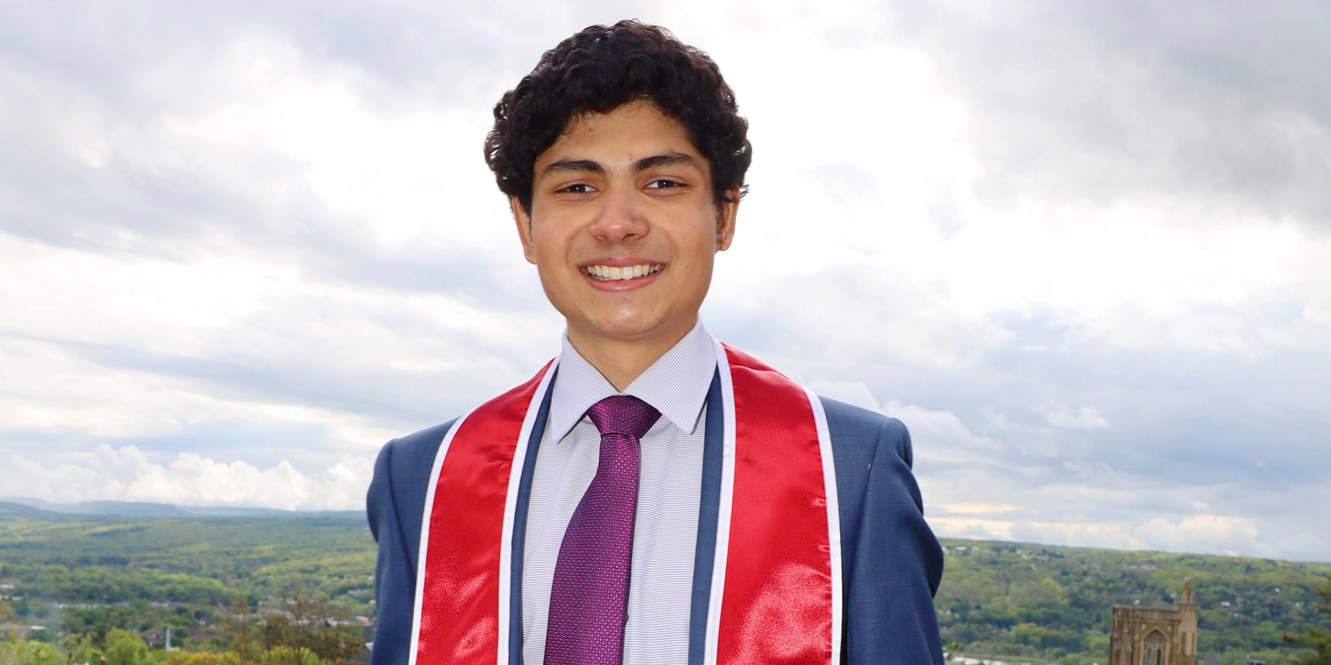A color photo of a man smiling for a photo outdoors.