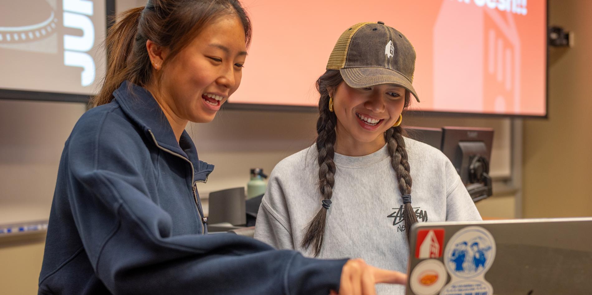 Two AppDev members stand around a computer and smile