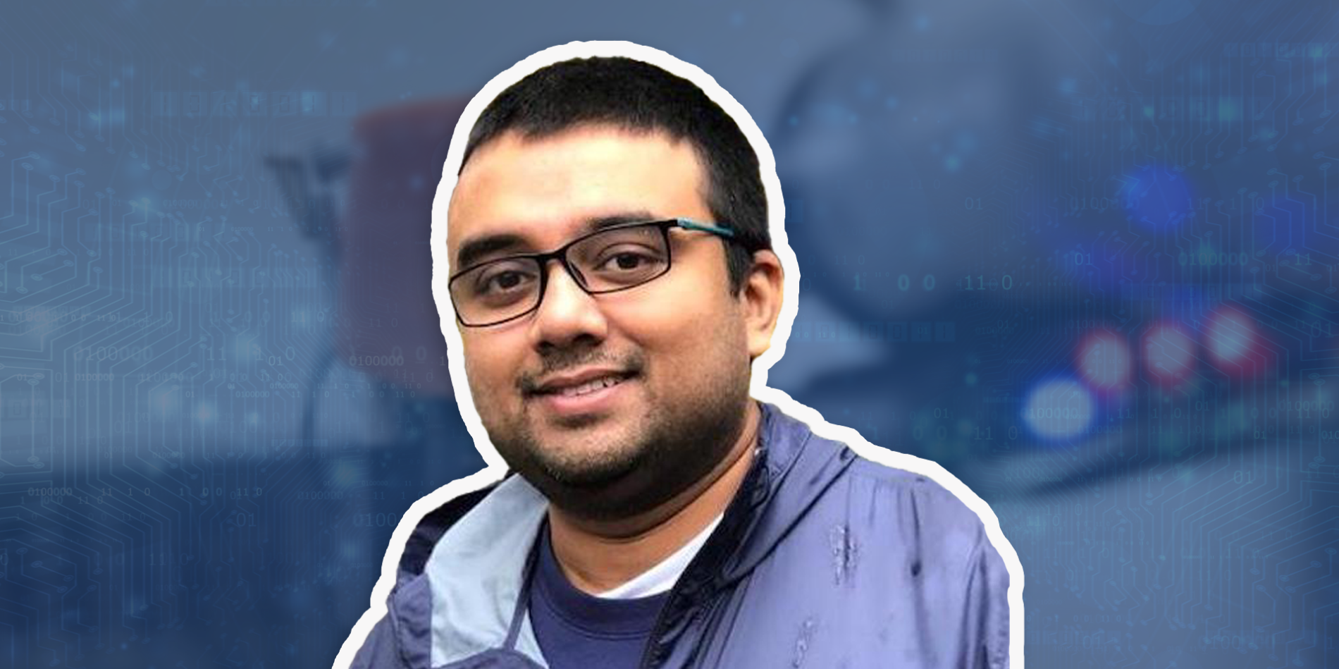 A man with glasses, tan skin and dark short hair smiles in front of a blue overlay background