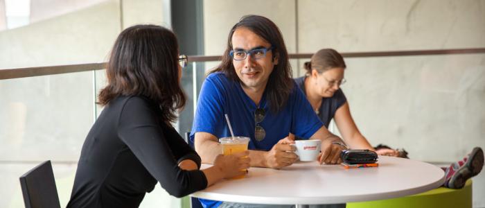 two people sit outside at a table with coffee