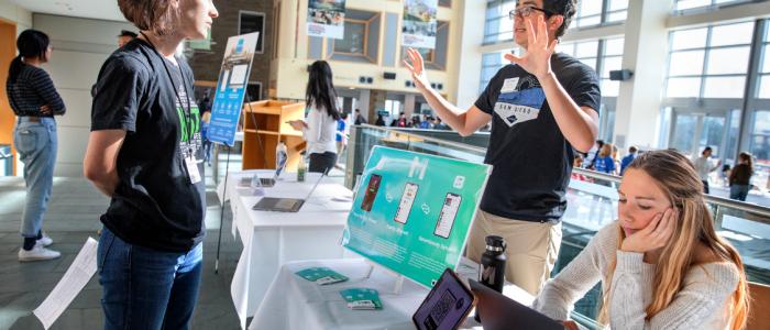 Students presenting a tech project at a campus showcase.