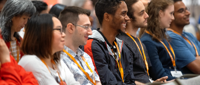 Audience of students smiling and listening during a conference.