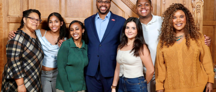 DEIB team of six people stand and pose against a wooden wall