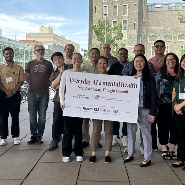 A color photo showing a group of people outside holding a large sign