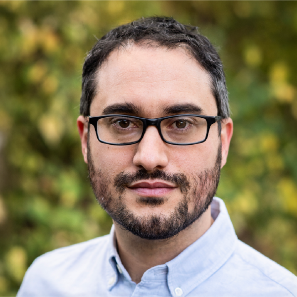 A color photo of a man standing outside.