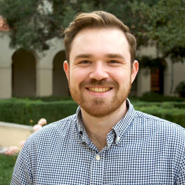A color photo of a man standing outside.