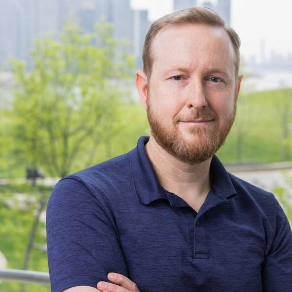 A color photo of a man smiling for a portrait.