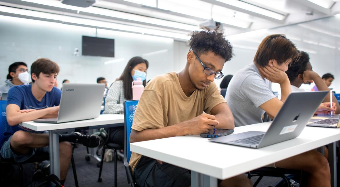 Students study on laptops in a classroom.