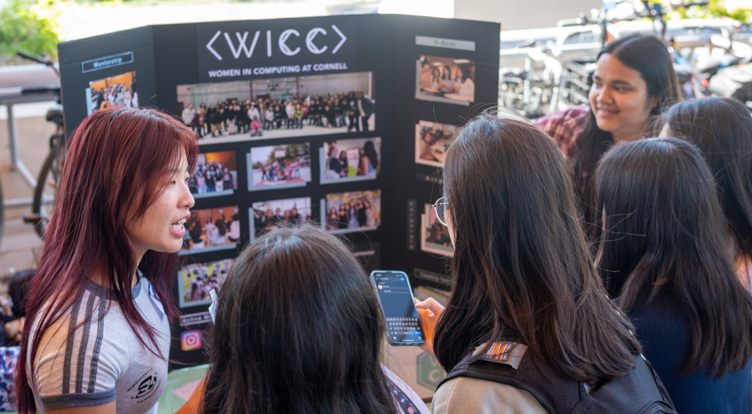At a student fair, women talk around a poster.