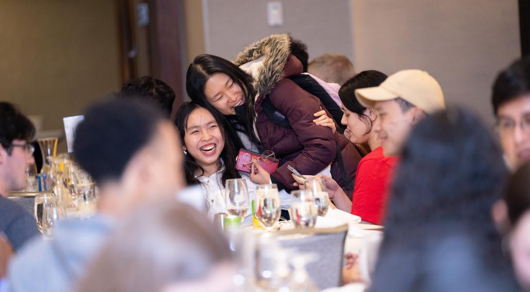 Students embrace and laugh at dinner.
