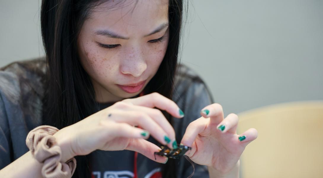 A color photo of a woman working on a small device.