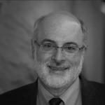 A black and white photo of Kenneth Birman, a man with glasses wearing a suit and tie.