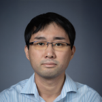 A color photo of asian man looking at camera, wearing glasses