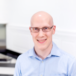 A color photo of Tyler Wilcox smiling for a photo