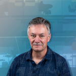 A color photo of James Booth in front of an abstract blue background