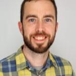 a man with short brown hair and a beard wearing a yellow and blue plaid shirt