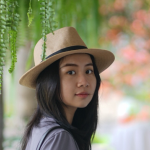 A color photo of a woman with dark hair wearing a hat.