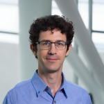 A color photo of a man smiling for a portrait.