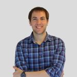 Man with short brown hair smiling at camera, wearing patterned shirt