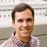 A photo of Anil Damle, a smiling man with brown hair and a red and white checked shirt.