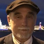 Man in suit and cap with beard looking at camera