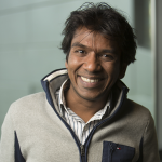 The head and shoulder of a man with black hair and a gray fleece.