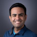 A photo of Christopher De Sa, a smiling man with short dark hair and a blue shirt.