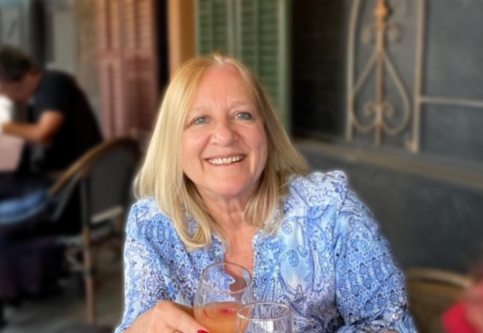 A color photo of Claudia Wojcinski sitting at an outdoor patio with a drink