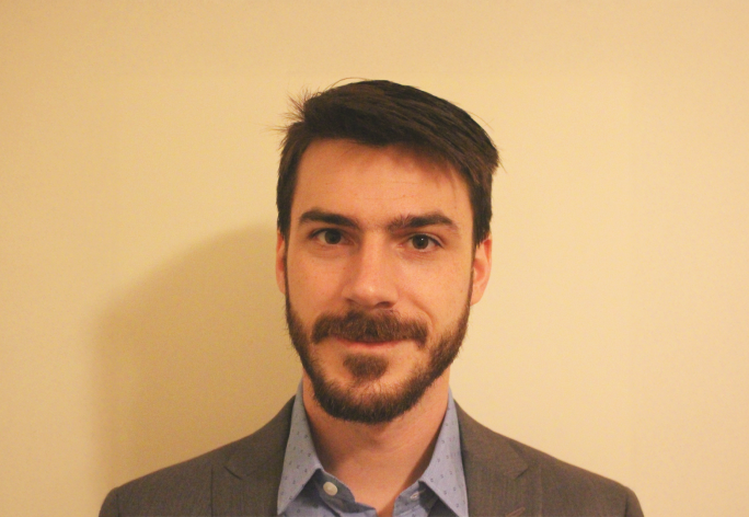 A color photo of Kirk Vanacore in front of a tan background