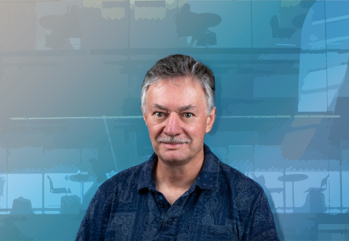 A color photo of James Booth in front of an abstract blue background