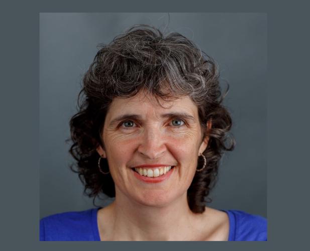 Portrait of woman smiling at camera, black curly hair