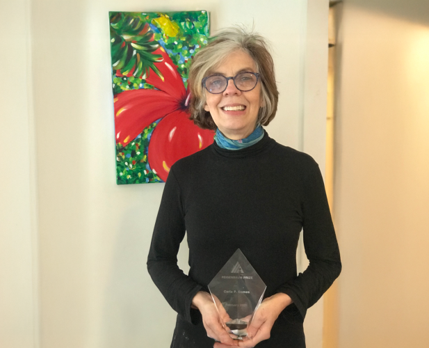 A color photo of a woman holding a glass award.