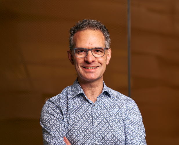 A photo of Stephen Marschner, a smiling man in front of a brown background