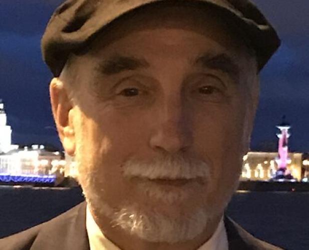 Man in suit and cap with beard looking at camera