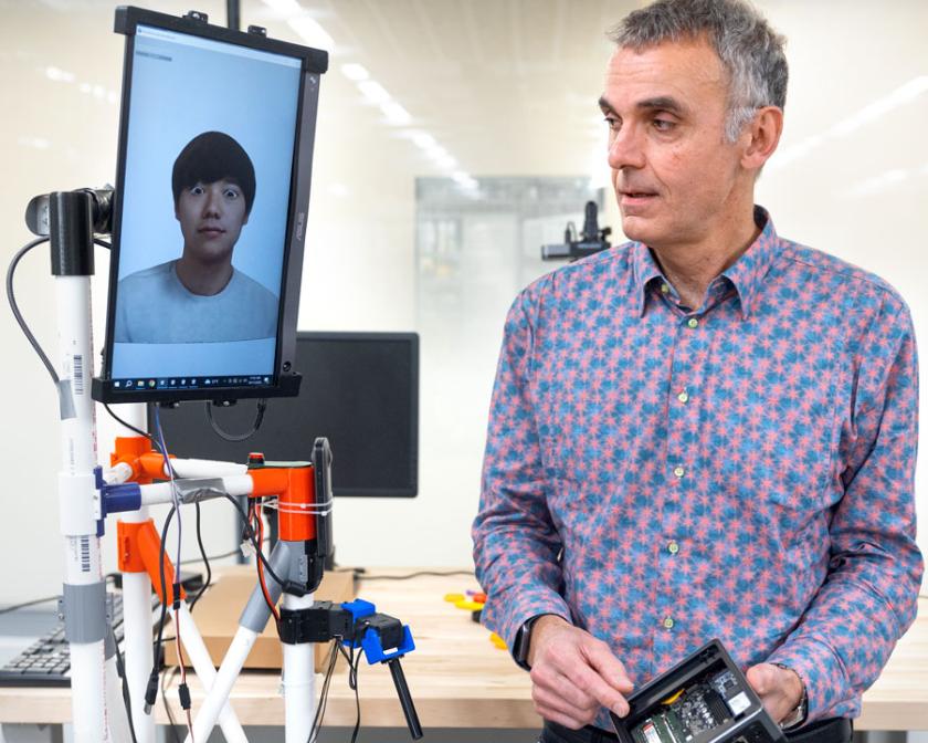 man in colorful shirt holding a remote that controls a tablet on a platform