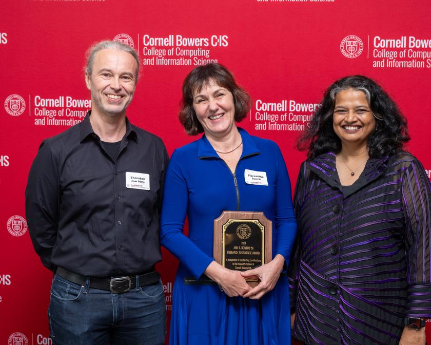 Three people stand in front of a red step and repeat.