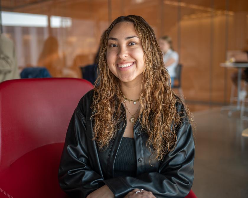 a female latino student sits on a red chair in gates hall