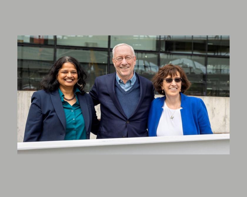 Three people pose next to beam