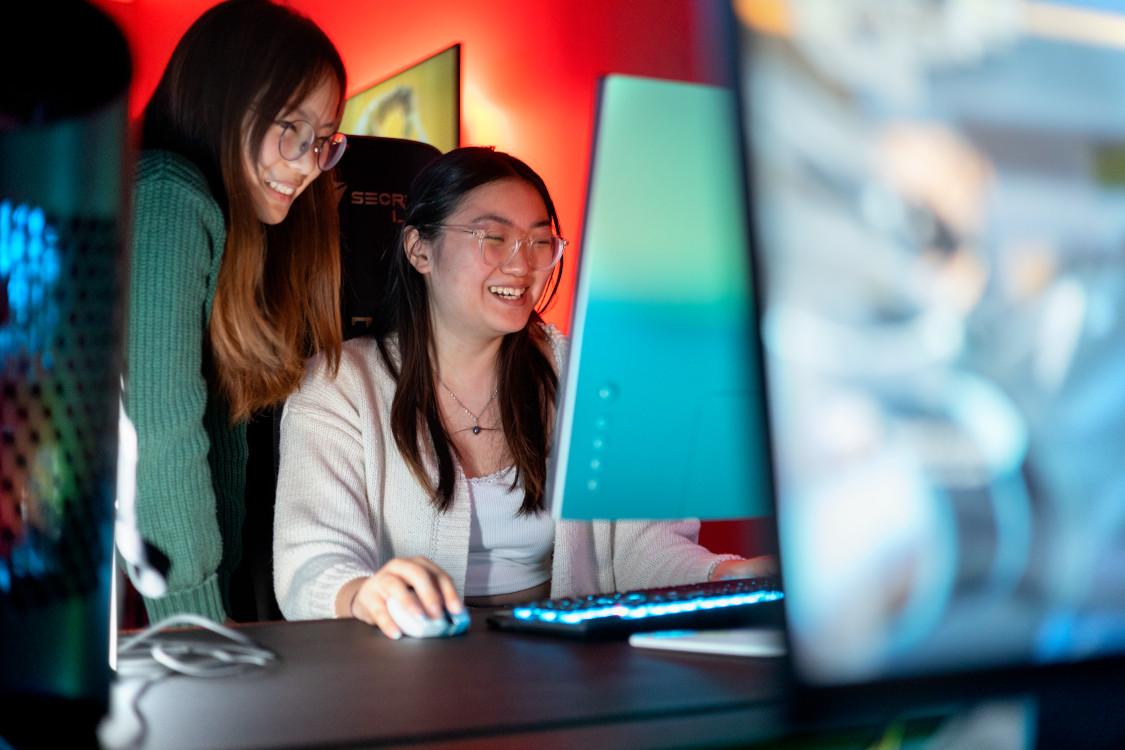 two female students work on a laptop 
